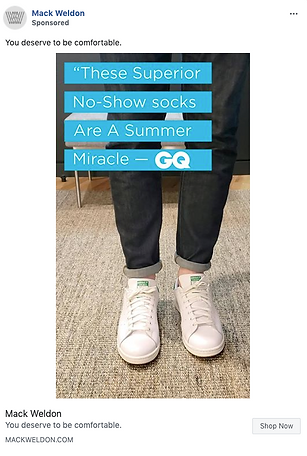 Person wearing white sneakers and no-show socks stands on a beige rug with a blue quote overlay about the socks being a "summer miracle" from GQ.