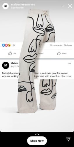 Beige pants with black abstract face and hand line drawings, displayed from the back. Social media post about the garment is partially visible in the background.