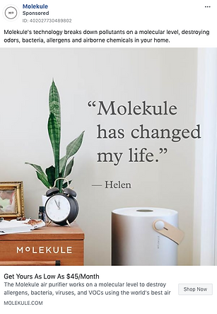 A Molekule air purifier sits on a table next to a clock and plant, with a testimonial quote on the wall reading, "Molekule has changed my life.