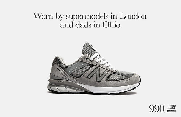 A grey New Balance 990 sneaker is displayed against a plain background with the text: "Worn by supermodels in London and dads in Ohio.