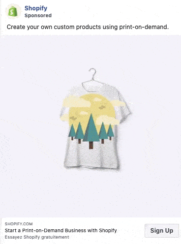 A white t-shirt with a graphic of trees and a yellow sun hangs on a hanger; text above reads, "Create your own custom products using print-on-demand.
