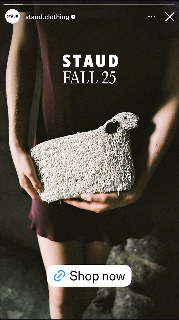 Person in a dark dress holds a textured white clutch bag; "STAUD FALL 25" text is displayed above, with a "Shop now" button at the bottom.