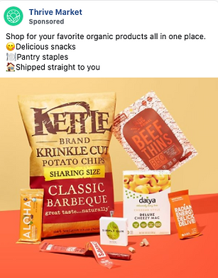 A selection of packaged organic snacks and pantry items, including chips, beef thins, cheezy mac, protein bar, and chocolate, displayed on an orange background.