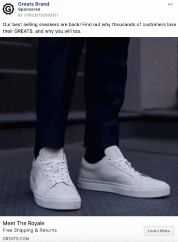 Close-up of a person wearing white sneakers and dark pants, standing on a textured surface. The image promotes Greats Brand sneakers.