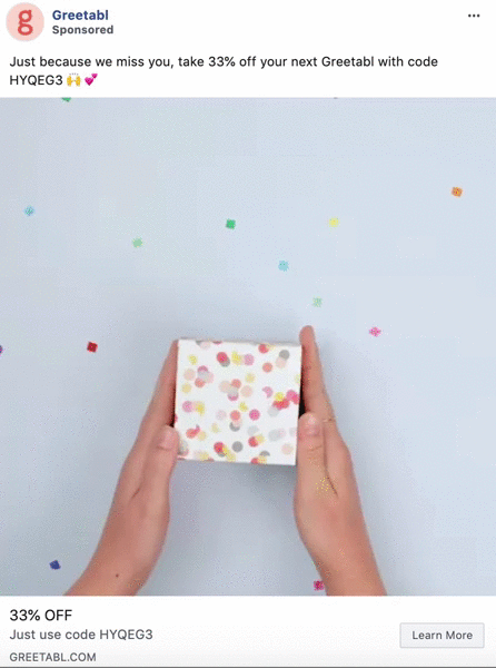 Hands holding and opening a small, colorful confetti-patterned gift box with confetti pieces scattered on a light blue background.
