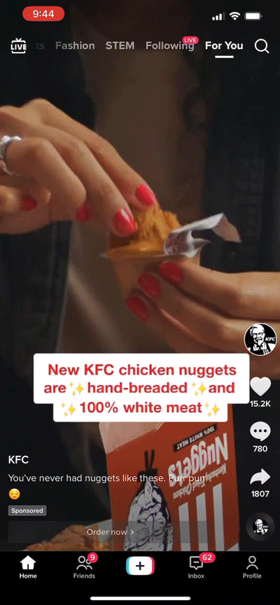 A person with red-painted nails dips a KFC chicken nugget into sauce; text overlay promotes KFC chicken nuggets as hand-breaded and made with 100% white meat.