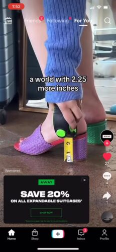 A person measures the height of their purple-heeled shoe with a tape measure, showing 2.25 inches. Text on screen reads, "a world with 2.25 more inches.