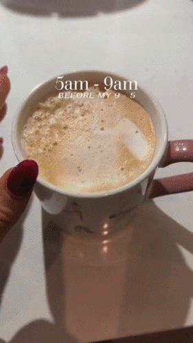 A hand stirs a foamy coffee in a white mug. Text on image reads "5am - 9am before my 9 - 5.