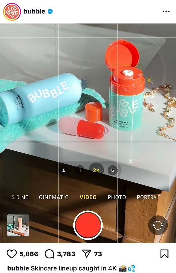 A bottle, jar, and two tubes of Bubble skincare products arranged on a bathroom counter with a gold chain and sunlight streaming in.