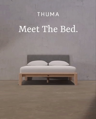 A minimalist wooden bed frame with a gray upholstered headboard is centered in a bare room. Text reads: "THUMA Meet The Bed.
