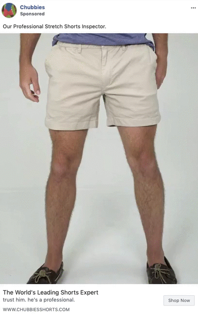 A person stands facing forward, wearing light-colored stretch shorts, a blue shirt, and brown boat shoes against a plain white background.
