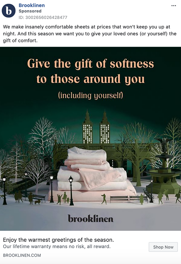 A stack of folded sheets and towels is displayed on a bench in a park with illustrations of trees and city buildings in the background. Text reads, "Give the gift of softness to those around you.