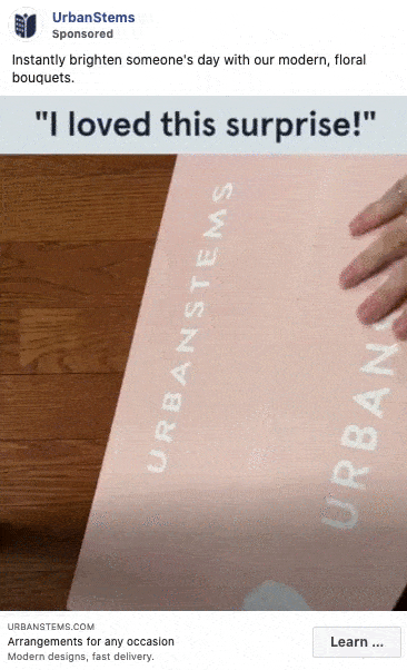 A person opens a pink UrbanStems box revealing a bouquet of yellow and white flowers, with the caption “I loved this surprise!” above.