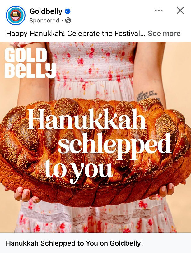 A person in a patterned dress holds a large loaf of braided challah bread with the text "Hanukkah schlepped to you" and "Goldbelly" overlaid.