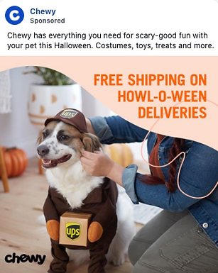 A dog dressed in a UPS delivery costume sits indoors while a person adjusts the outfit. Halloween decorations and pumpkins are visible in the background.