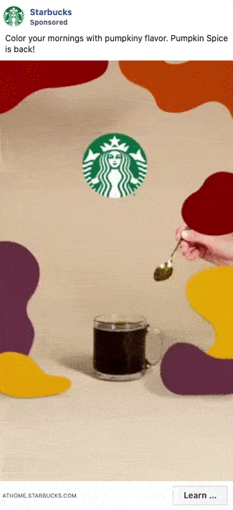 A hand sprinkles pumpkin spice over a glass mug of black coffee, with the Starbucks logo and colorful abstract shapes in the background.