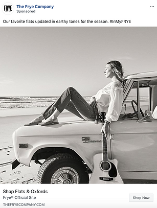 A woman sits on the hood of a vintage truck parked on a beach, with a guitar leaning against the vehicle. The image is black and white.