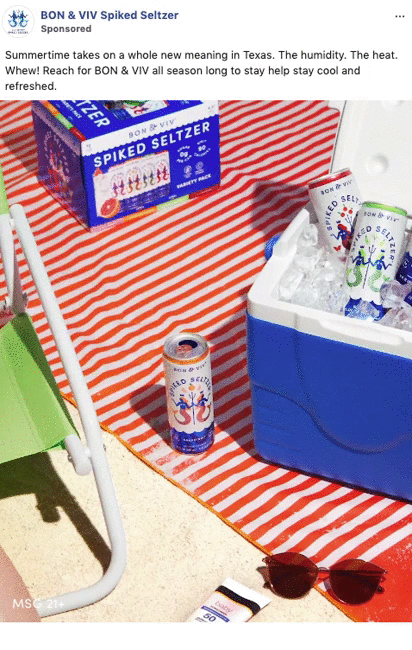 A cooler filled with BON & VIV spiked seltzer cans stands next to a beach chair, sunglasses, a magazine, and a seltzer can on a towel. A case of the seltzer is in the background.