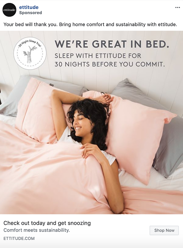 A person lies in bed smiling with pink sheets and pillows, beneath a sign promoting ettitude bedding and a 30-night sleep trial.