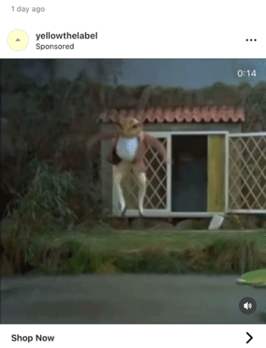 A person in a rabbit costume jumps off the steps of a small house set with a lattice door and grass.