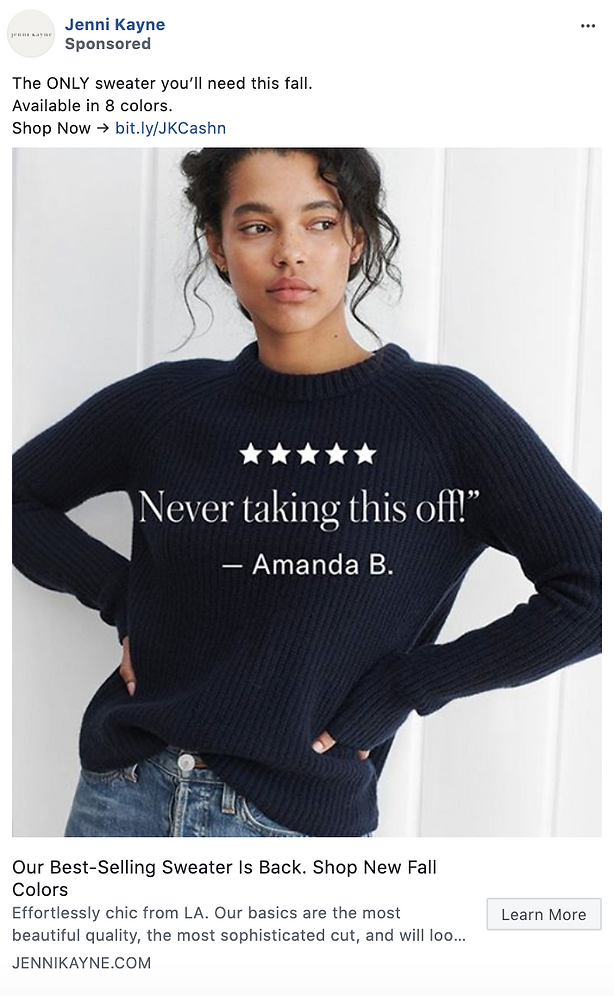 Woman wearing a dark navy ribbed sweater with arms crossed, standing against a light background. Text overlay reads, "Never taking this off! — Amanda B.