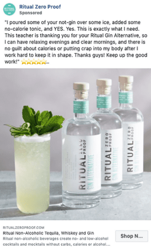 Three bottles of Ritual Zero Proof non-alcoholic spirits are displayed behind a glass of a light green cocktail garnished with mint leaves on a white table.