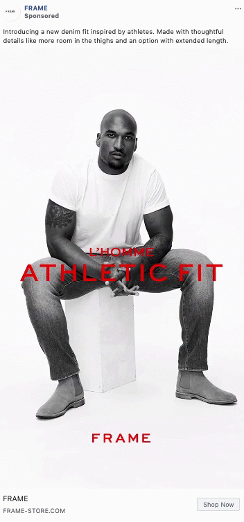 A man in a white t-shirt and jeans sits on a white block, modeling denim for FRAME’s "Athletic Fit" collection against a plain white background.