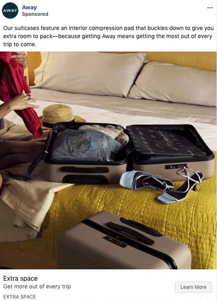 A person packs a suitcase with an interior compression pad on a bed, with another closed suitcase nearby in a modern, well-lit bedroom.