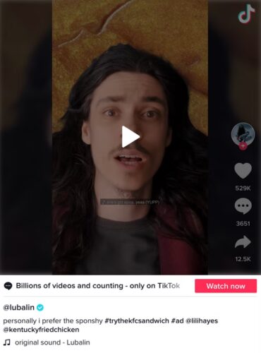 A person with long dark hair lies on a surface, looking up at the camera in a paused TikTok video. TikTok interface elements are visible, including likes and comments.