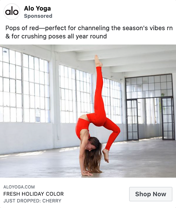 Woman in a spacious, sunlit studio wearing bright red yoga attire performs a handstand with one leg bent and the other extended upward.