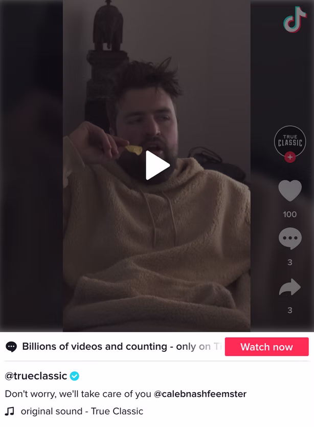 A man in a beige hoodie sits indoors eating a snack, with TikTok interface elements visible on the right side of the screen.