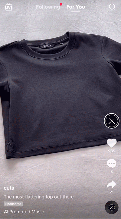 A plain black short-sleeve crop top is laid flat on a white surface, shown in a TikTok video with engagement icons and text overlay at the bottom.