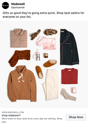 Flat lay of women's clothing and accessories including pajamas, a sweater, pants, slippers, socks, a mug, and a candle arranged on a white background.