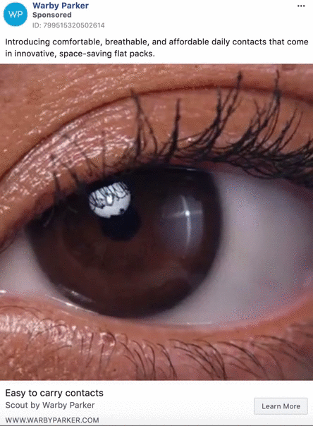 Close-up of a human eye with a reflection of the Warby Parker logo, advertising daily contact lenses in flat packs.