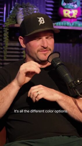 A man in a black shirt and cap speaks into a microphone in a studio. White text on screen reads, "It's all the different color options.