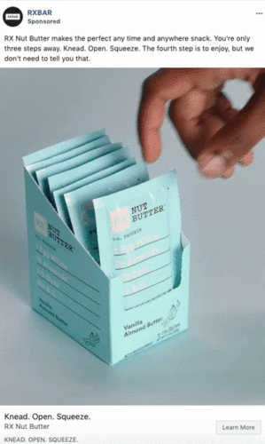 A hand reaches for a packet of RX Nut Butter from an open box containing several individual blue packets labeled "Vanilla Almond Butter.