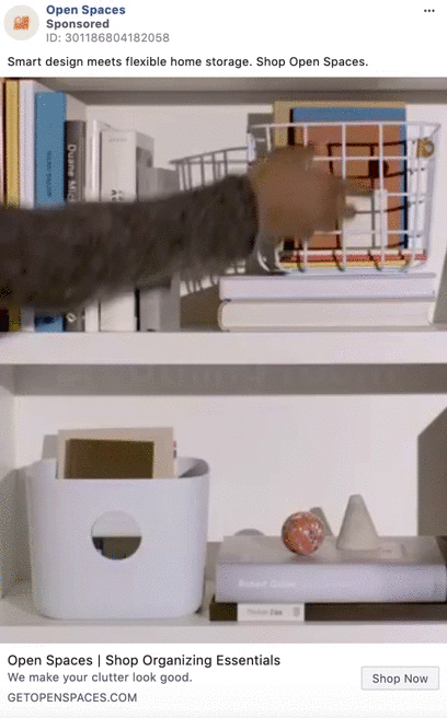 A person places an orange notebook into a white wire storage basket on a shelf with books and organizers.