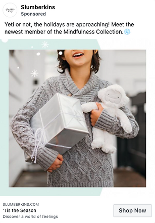 A child in a gray sweater holds a silver gift box and a white plush toy, smiling. Holiday decorations and text about the Mindfulness Collection are visible.