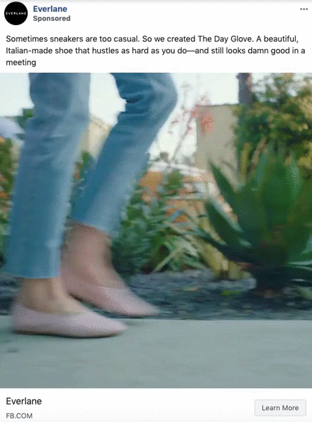 Close-up of a person walking outdoors on a path, wearing light pink slip-on shoes and light blue jeans, with greenery in the background.