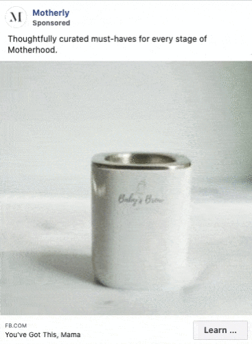 A stainless steel Baby's Brew bottle warmer displayed on a light surface, featured in a sponsored ad by Motherly for parenting essentials.