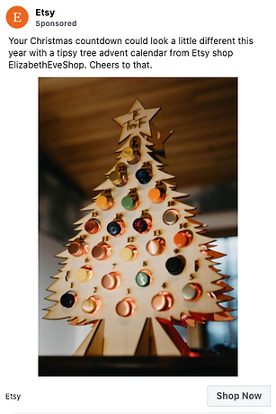 A wooden Christmas tree-shaped advent calendar holds miniature bottles of alcohol, with festive ornaments and lights in the background.