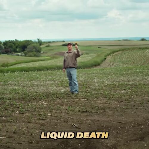 A person stands in a field holding up a can, with the words "LIQUID DEATH" in bold text at the bottom of the image.
