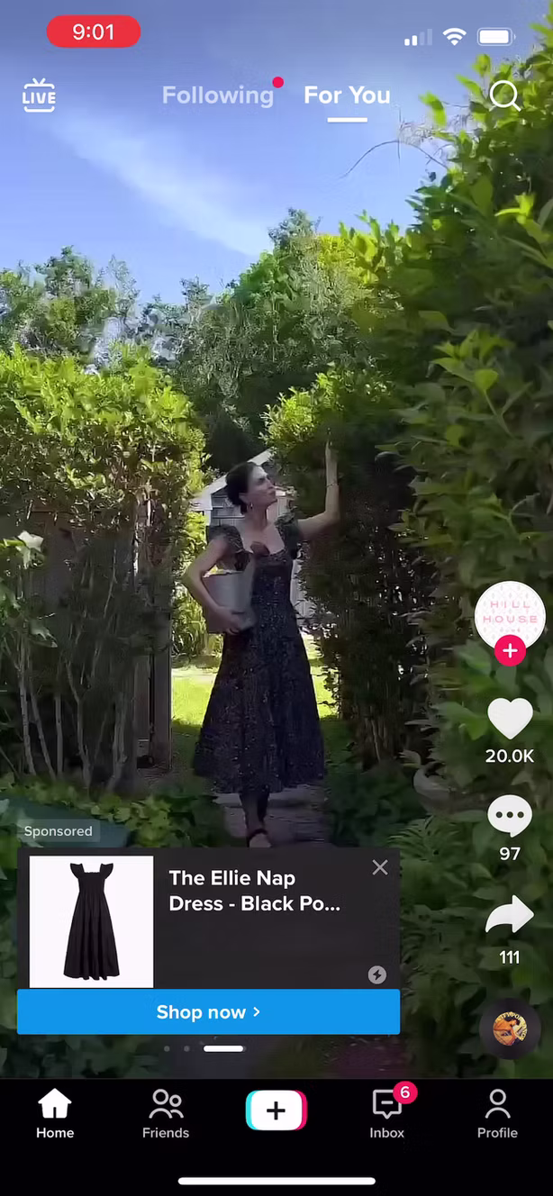 A woman in a black dress stands in a garden, posing with one arm raised. The TikTok interface and an ad for a black dress are visible on the screen.