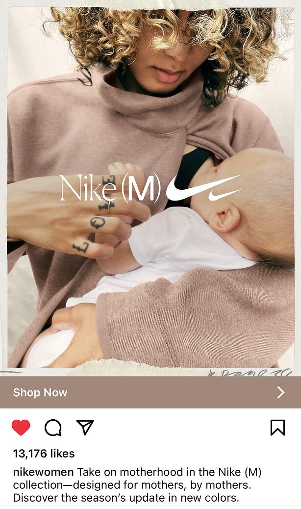 A woman wearing a mauve poncho-style top breastfeeds a baby while seated indoors. The Nike (M) logo is overlaid on the image.