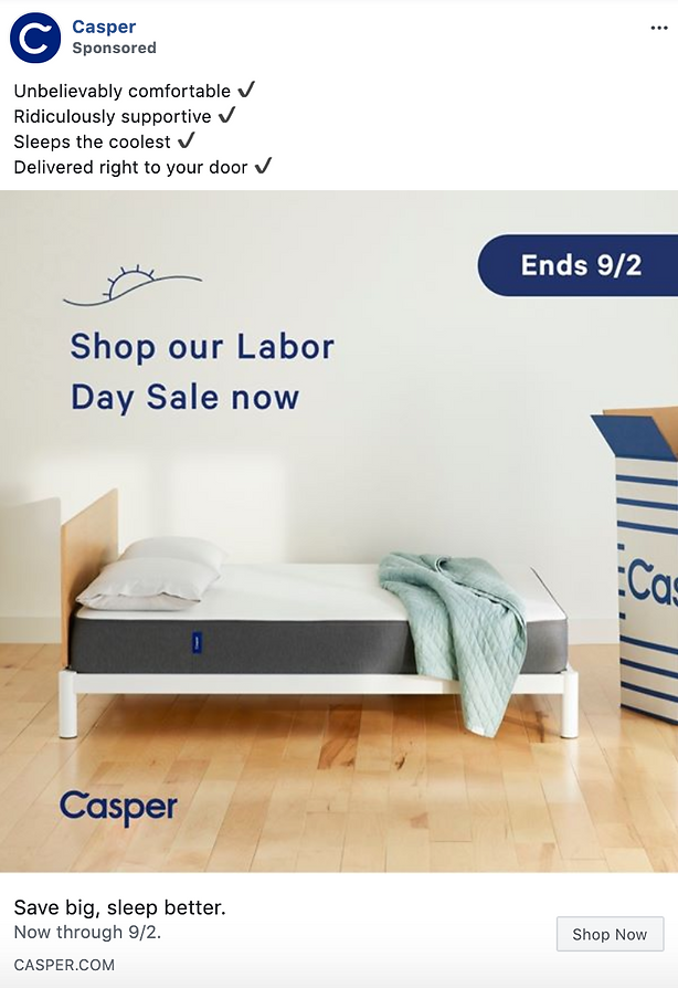 A neatly made bed with a gray mattress and light blue quilt sits beside a large cardboard box in a bright, minimalist room. Text promotes a Labor Day sale ending 9/2.