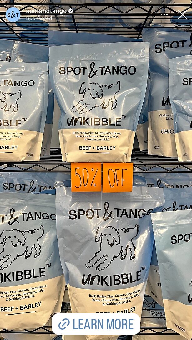 Bags of Spot & Tango UnKibble Beef & Barley dog food are displayed on shelves with a "50% OFF" sign in the center.