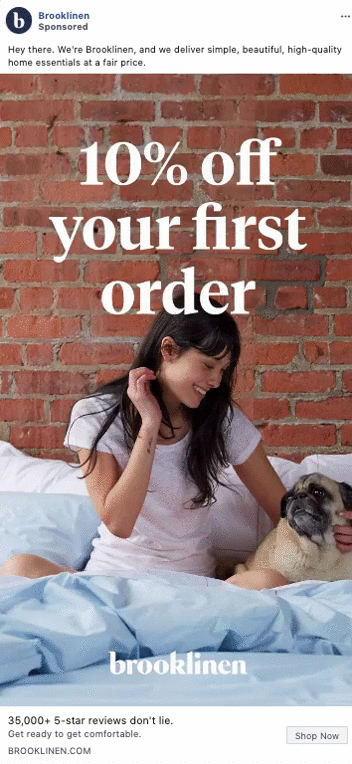 Woman sitting on a bed with blue bedding, smiling at a dog. Text overlay offers 10% off first order from Brooklinen.