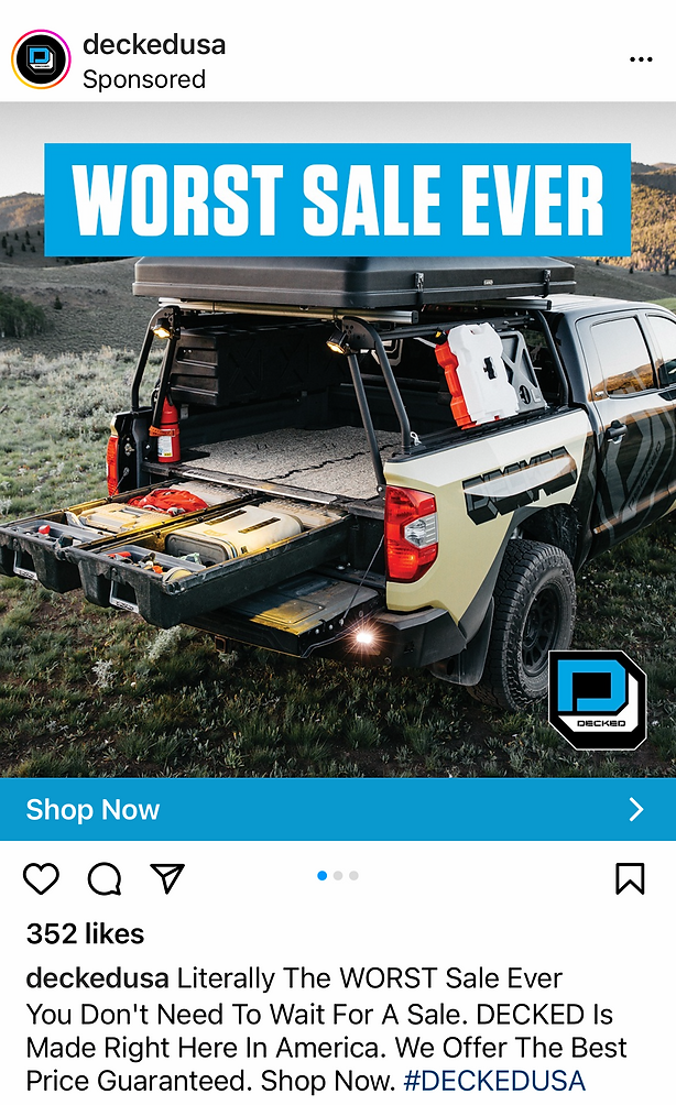 A pickup truck with an open tailgate and storage system is parked on grass, showcasing outdoor gear and equipment beside a "WORST SALE EVER" banner.