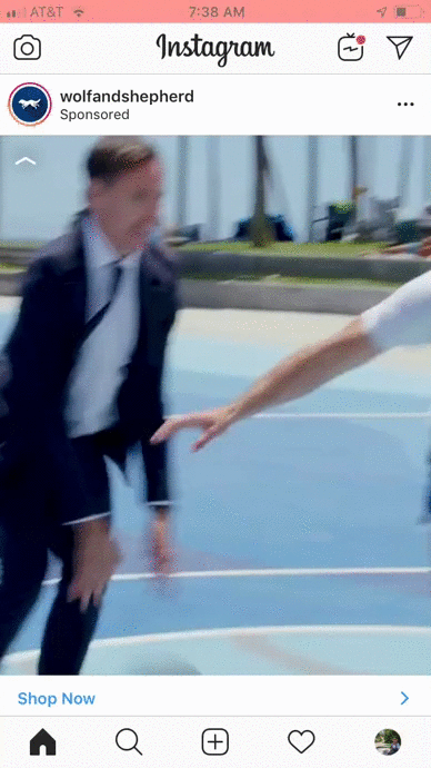 A man in a suit plays basketball against a casually dressed opponent on an outdoor court near palm trees.
