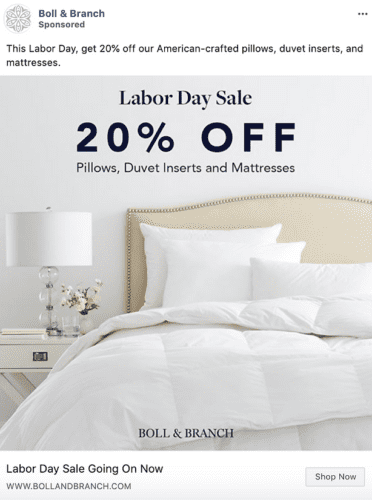 A neatly made bed with white bedding and pillows, a nightstand with a lamp, and text announcing a 20% off Labor Day sale on pillows, duvet inserts, and mattresses.
